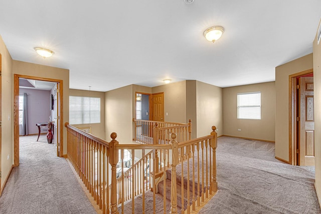 corridor with light carpet, baseboards, and an upstairs landing
