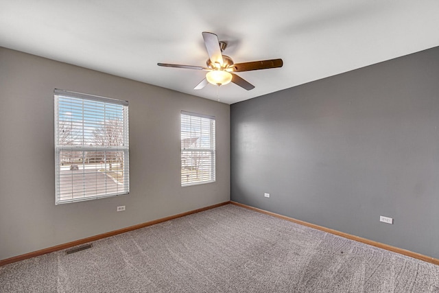 unfurnished room with carpet, visible vents, baseboards, and ceiling fan