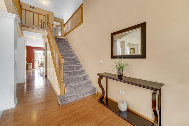 stairway with visible vents, wood finished floors, and baseboards