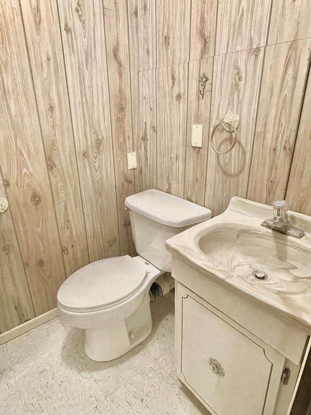 bathroom with wooden walls, toilet, and vanity