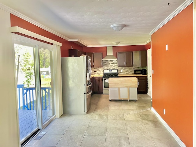 kitchen with appliances with stainless steel finishes, wall chimney range hood, decorative backsplash, crown molding, and butcher block countertops