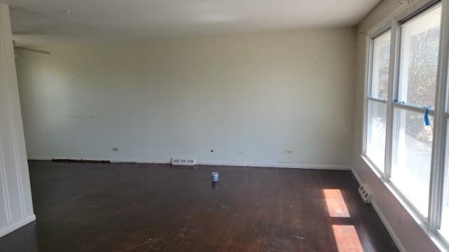 unfurnished room featuring visible vents, baseboards, ceiling fan, and dark wood finished floors