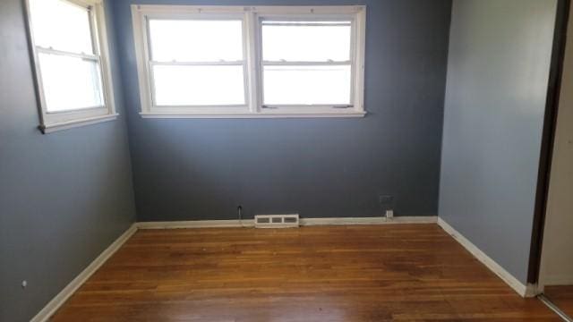 unfurnished room with visible vents, baseboards, and wood finished floors