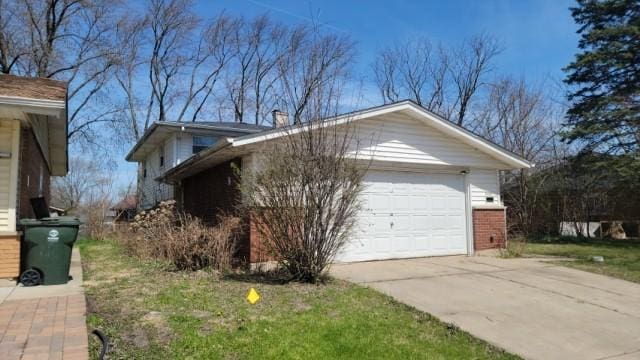 view of side of property featuring concrete driveway, brick siding, and a chimney