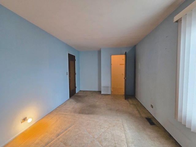 spare room featuring light carpet and visible vents