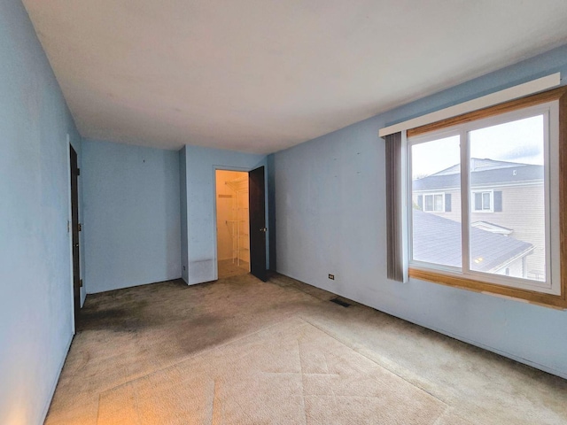 spare room featuring visible vents and light carpet