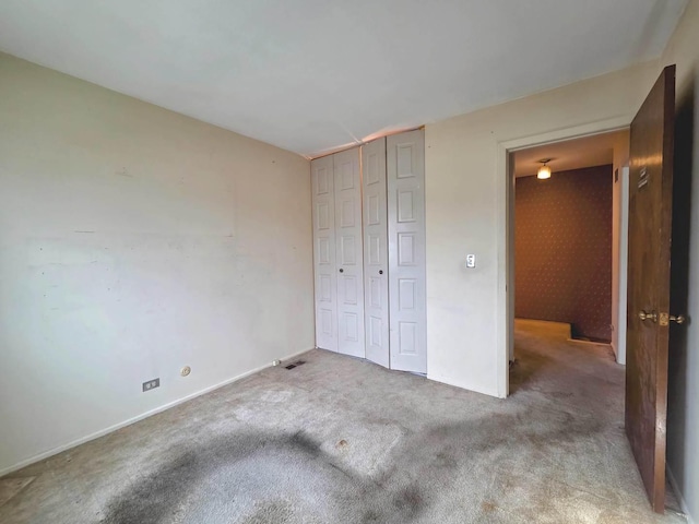 unfurnished bedroom featuring carpet floors, baseboards, and a closet