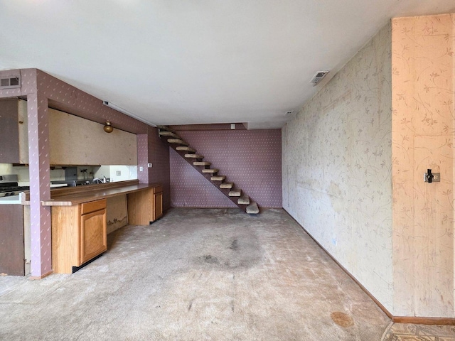 below grade area with stairs, light colored carpet, wallpapered walls, and visible vents