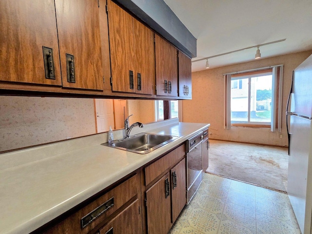 kitchen featuring a sink, light countertops, freestanding refrigerator, dishwashing machine, and light floors