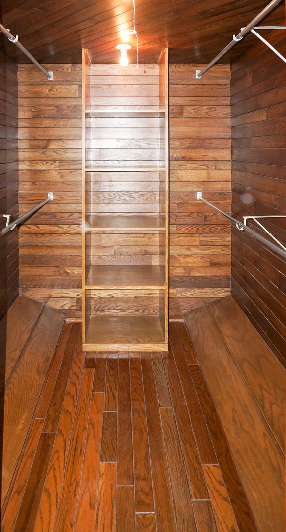 bathroom featuring wood ceiling, a tile shower, and wood walls
