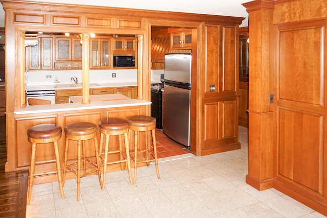kitchen featuring freestanding refrigerator, built in microwave, a breakfast bar area, and a peninsula
