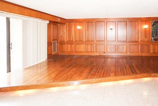 unfurnished room with visible vents, wood-type flooring, and a decorative wall