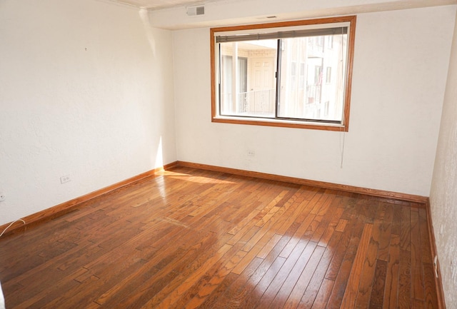 unfurnished room with baseboards, wood-type flooring, and visible vents