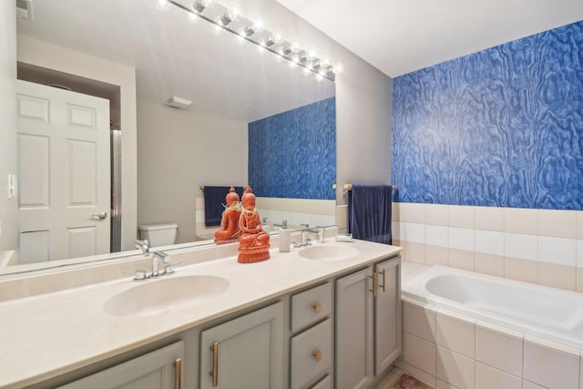 bathroom with wallpapered walls, a garden tub, double vanity, and toilet