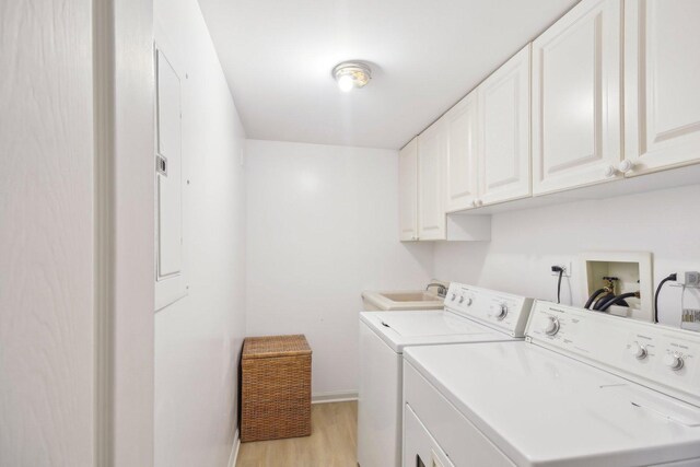 clothes washing area featuring cabinet space, washer and dryer, light wood-type flooring, and baseboards