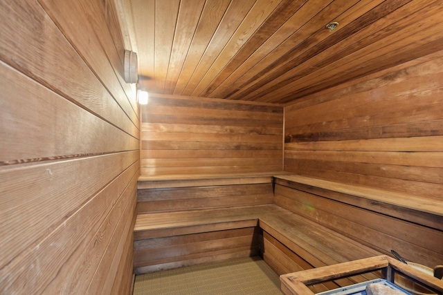relaxing sauna featuring wooden walls and wooden ceiling