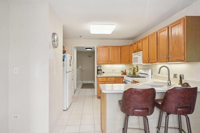 kitchen with white appliances, a peninsula, a sink, light countertops, and light tile patterned flooring