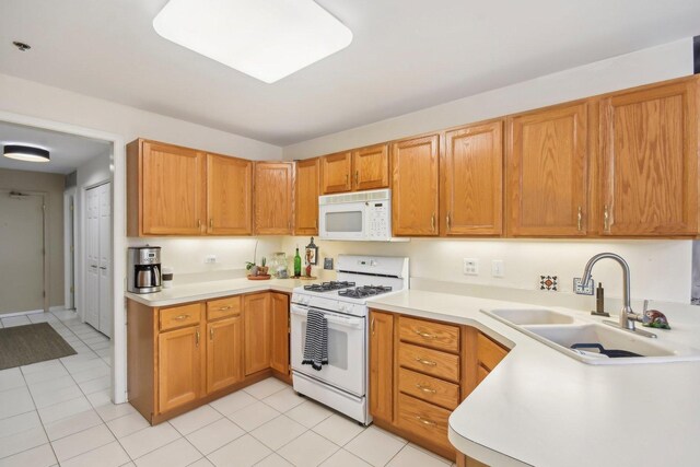 kitchen with white appliances, a sink, light countertops, light tile patterned flooring, and brown cabinetry