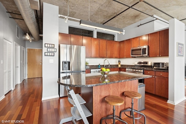 kitchen featuring appliances with stainless steel finishes, dark wood-type flooring, tasteful backsplash, and a high ceiling