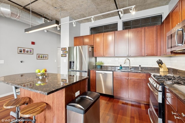 kitchen featuring stainless steel appliances, dark wood-type flooring, a sink, and rail lighting