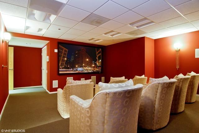 carpeted home theater with a drop ceiling and baseboards