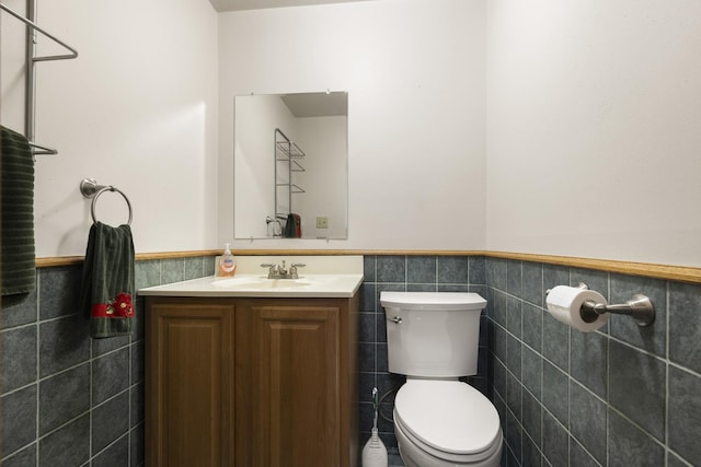bathroom with vanity, tile walls, wainscoting, and toilet