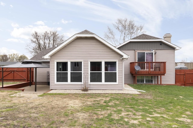 back of property featuring fence, a shingled roof, a lawn, and a chimney