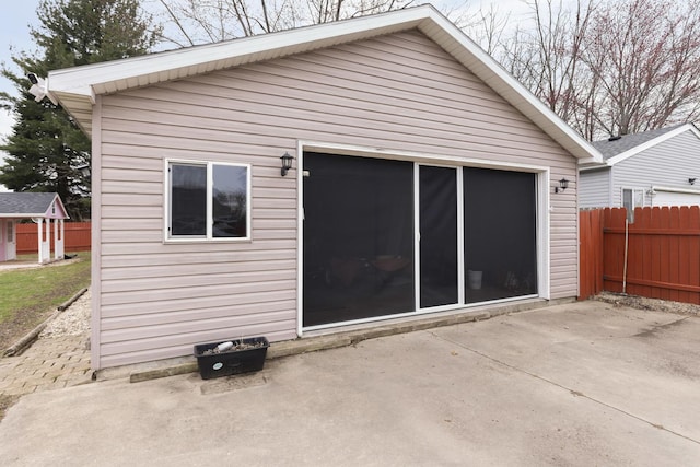 back of property featuring fence, an outdoor structure, and a patio