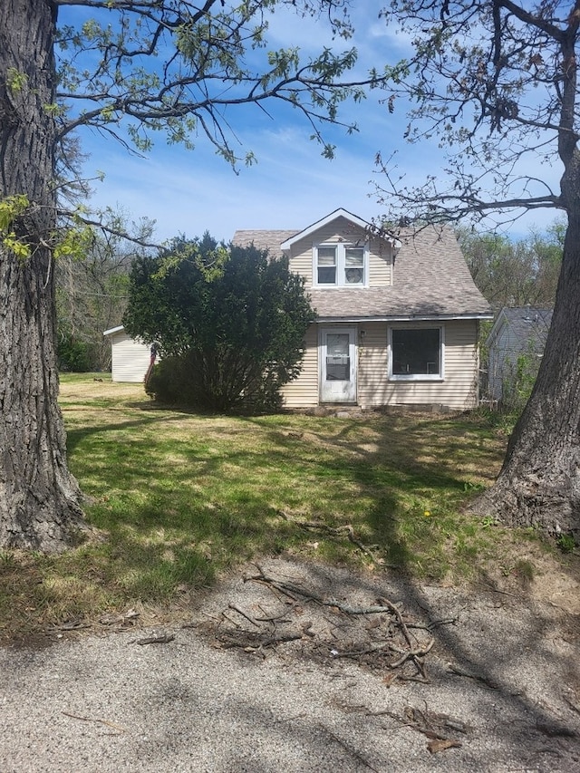 view of side of home with a yard and roof with shingles