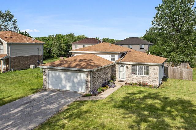 mediterranean / spanish-style house featuring an attached garage, fence, central AC unit, a front yard, and driveway