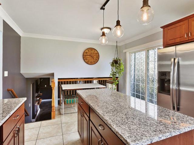 15535 Homan Ave, Markham, IL 60428 - kitchen featuring stainless steel fridge with ice dispenser, a center island, ornamental molding, light stone counters, and light tile patterned floors