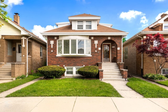 bungalow featuring a front lawn, brick siding, and roof with shingles