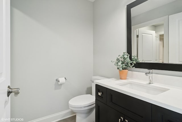 half bath featuring vanity, baseboards, tile patterned flooring, and toilet