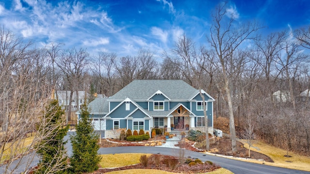craftsman house with roof with shingles, curved driveway, and a porch