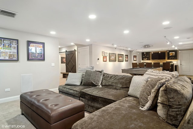 living room featuring a barn door, bar, rail lighting, baseboards, and visible vents