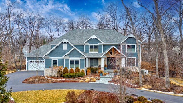 craftsman inspired home with roof with shingles, stone siding, a garage, aphalt driveway, and a porch