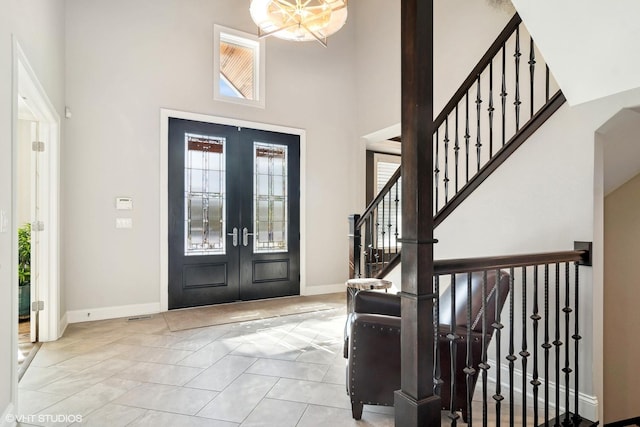 foyer featuring baseboards, a high ceiling, french doors, and stairs