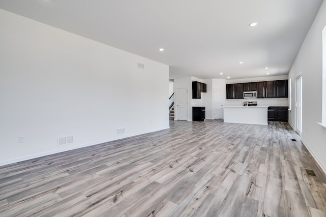 unfurnished living room with stairs, recessed lighting, visible vents, and light wood-style floors