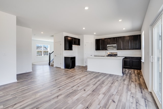 kitchen with light countertops, appliances with stainless steel finishes, light wood-style flooring, and open floor plan