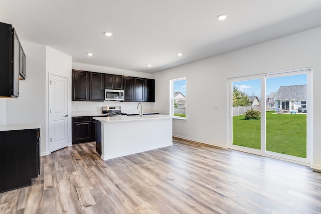 kitchen with a sink, light countertops, light wood-style floors, stainless steel appliances, and recessed lighting