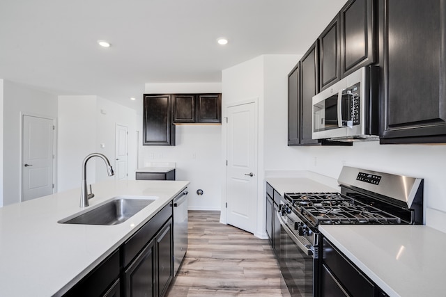 kitchen featuring a sink, light wood-style flooring, appliances with stainless steel finishes, and light countertops