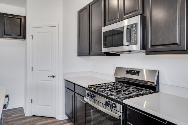 kitchen with light countertops, appliances with stainless steel finishes, wood finished floors, and dark brown cabinetry