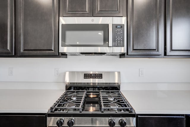kitchen featuring gas range oven, stainless steel microwave, dark brown cabinetry, and light countertops