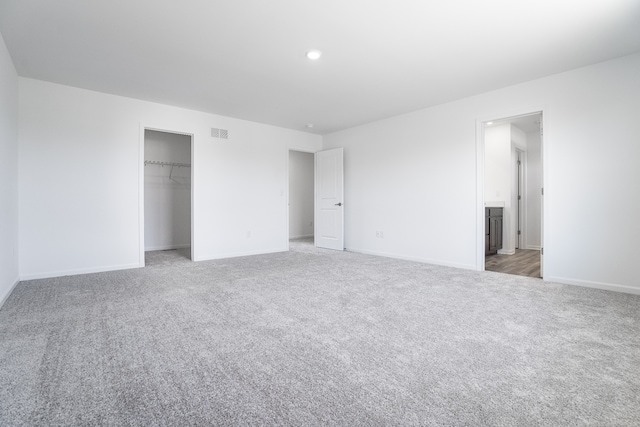 unfurnished bedroom featuring baseboards, a closet, visible vents, and light carpet