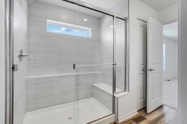 bathroom with a shower stall, wood finished floors, and visible vents