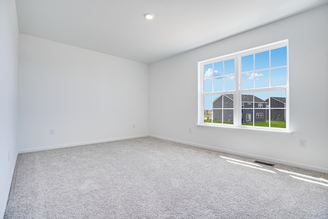 carpeted spare room featuring baseboards and visible vents