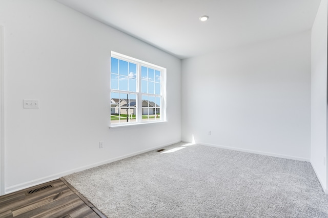 spare room featuring baseboards, wood finished floors, and visible vents