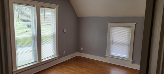 spare room featuring baseboards, vaulted ceiling, and wood finished floors