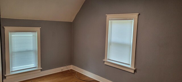 unfurnished room featuring baseboards, vaulted ceiling, and wood finished floors