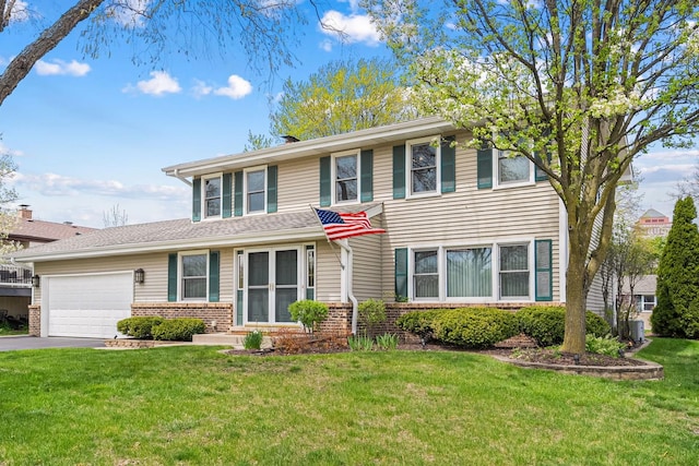 traditional home featuring brick siding, an attached garage, a front yard, and aphalt driveway